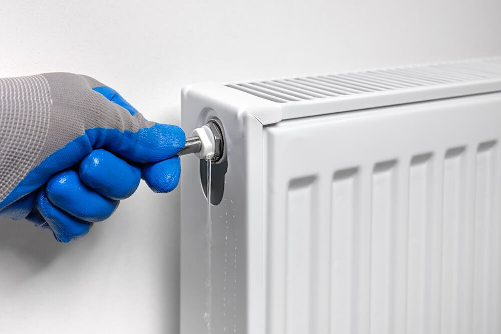 A plumber uses a radiator bleed key to drain air, draining water and air from a radiator in an apartment. Air bleed valve in a heating radiator.